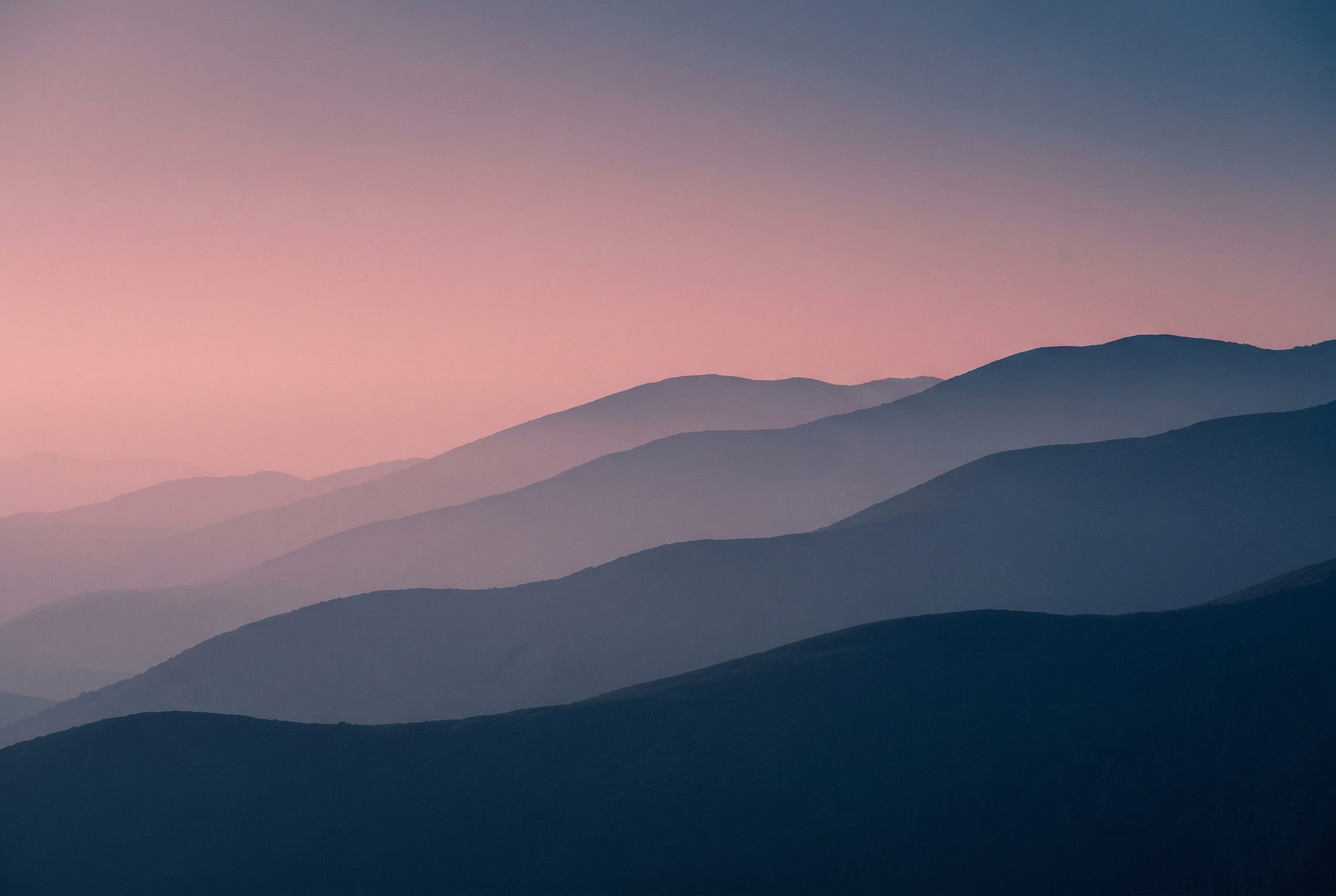 Gestaffelte Bergketten im Abenddunst, rosa Himmel